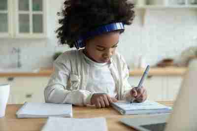 A picture of a girl writing on a piece of paper with a pen
